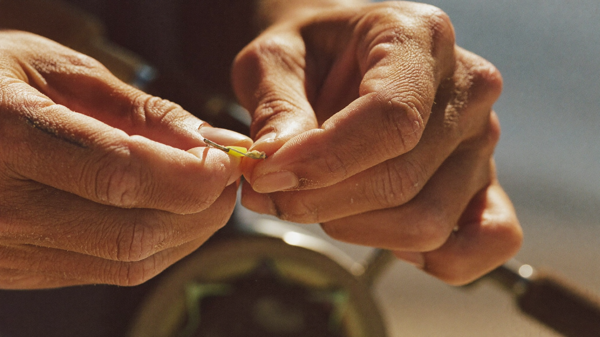 Weathered hands tying a fishing knot, close up