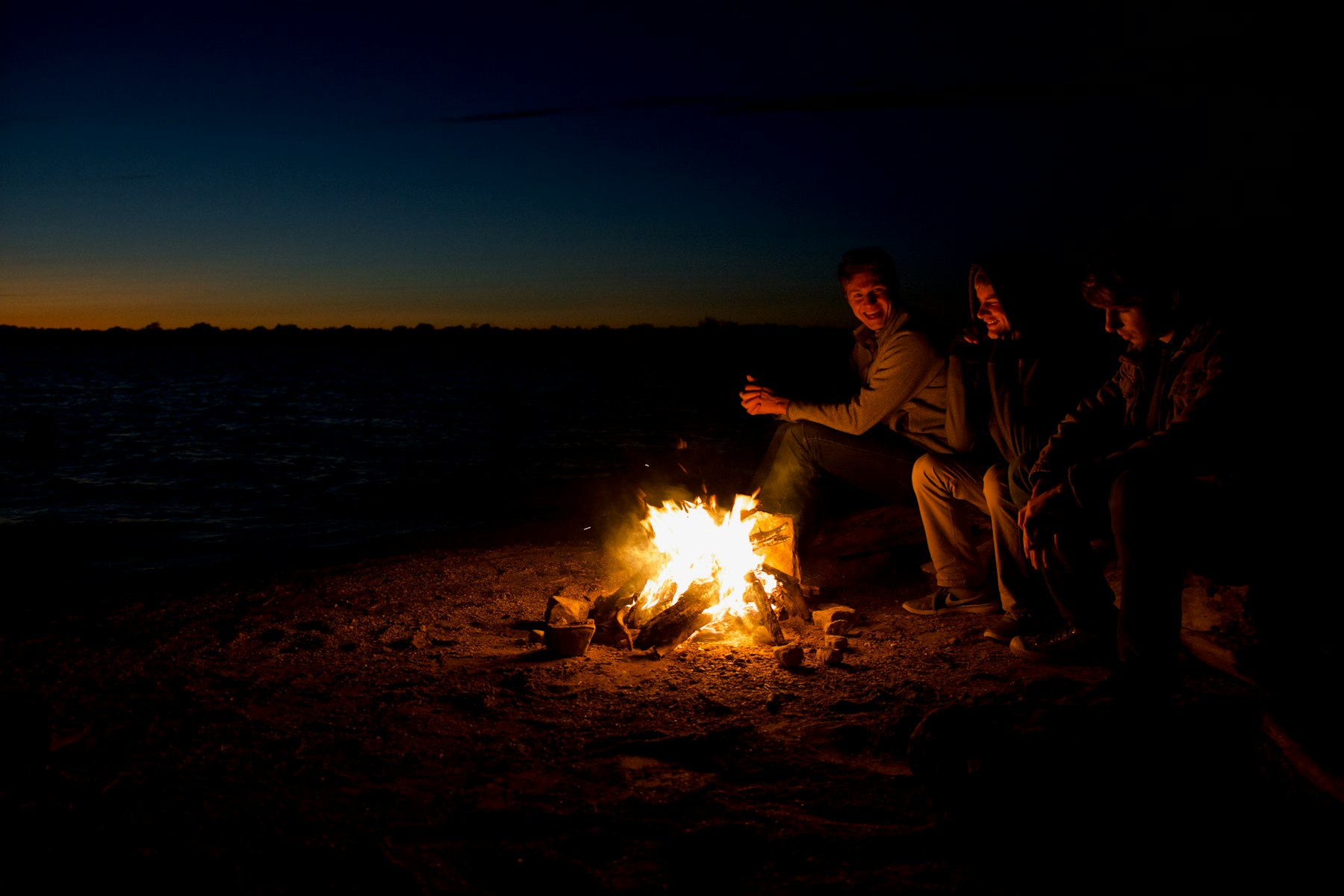 A group gathered around a beach fire at night