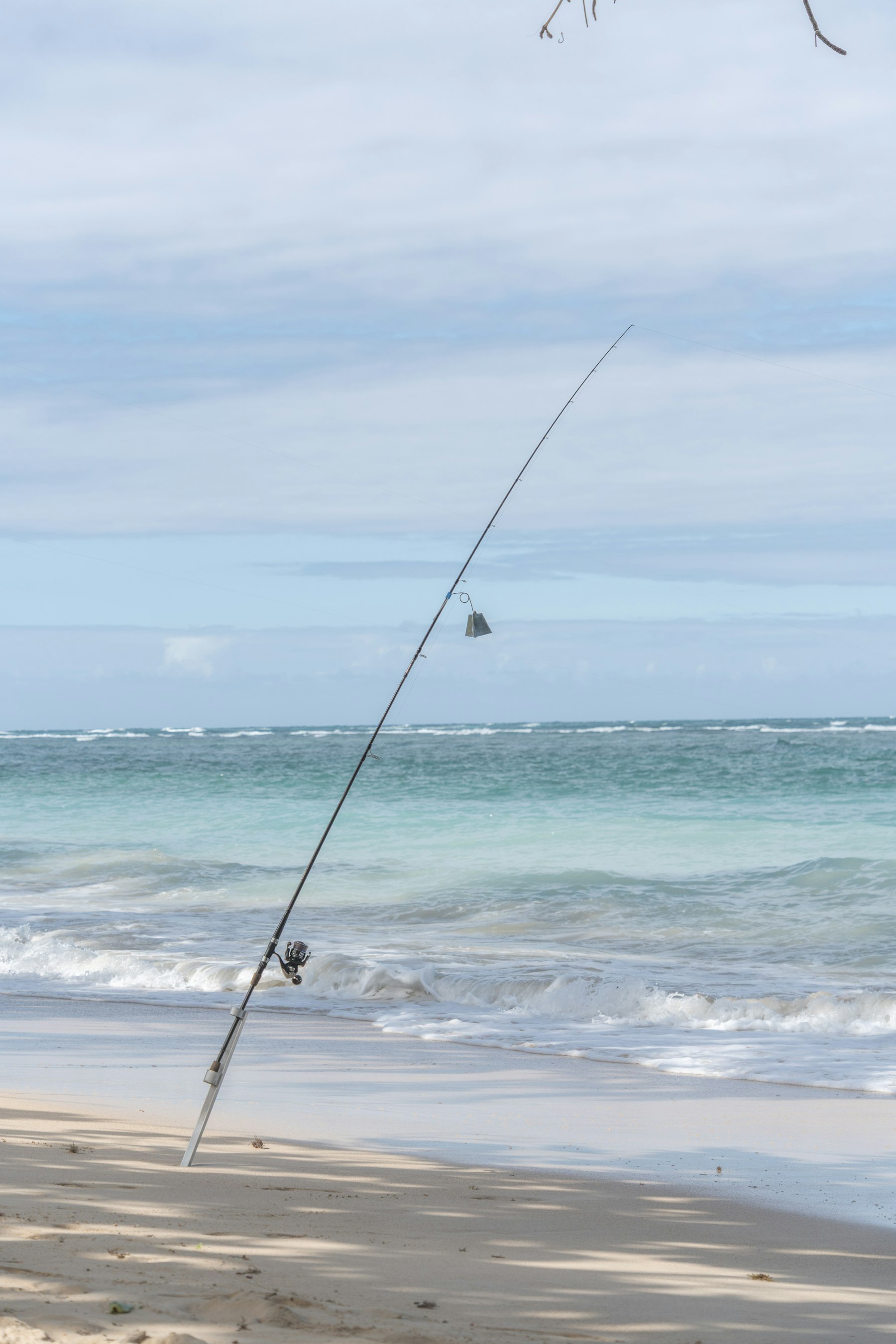 A surf rod set in a sand-spike with a bite bell, waiting in the Galveston surf